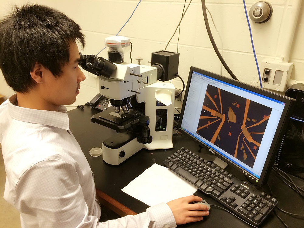 Purdue University doctoral student Yang Xu, lead author of a new research paper on "topological insulators," an emerging class of materials that could make possible "spintronic" devices and practical quantum computers far more powerful than today's technologies, is shown here inspecting devices made from topological insulators under a microscope before electrical measurements. (Purdue University photo / Ting-fung Chung) 