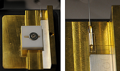 Nearly transparent, this lithium niobate crystal (just visible just above the white square section at bottom right) is capable of splitting a beam of photons into two beams of two different colors, an innovation that may help send quantum information through fiber optic cables, one of which is attached to the crystal at its top left corner and extends straight upward to the top of the photo frame. Credit: Talbott/NIST