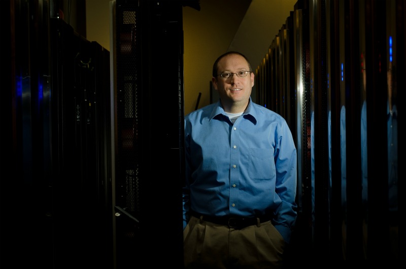 Kevin Regimbal, director of the PNNL Institutional Computing program, stands next to PNNL's Olympus supercomputer.  