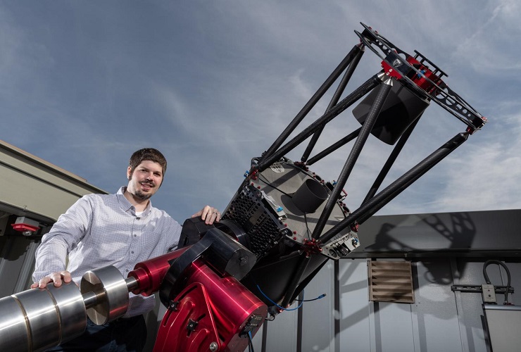 CAPTION Astrophysicist Billy Quarles, author of a new study on exoplanet axis tilt, stands with Georgia Tech's largest telescope housed at its observatory.  CREDIT Georgia Tech / Rob Felt