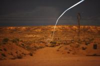 A tiny light-emitting diode, or LED, attached to a self-guided bullet at Sandia National Laboratories shows a bright path during a nighttime field test that proved the battery and electronics could survive the bullet's launch.