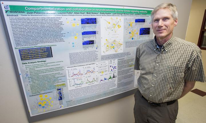 CAPTION UM cell biologist Mark Grimes stands in front of a poster displaying the findings in his research paper. CREDIT Todd Goodrich