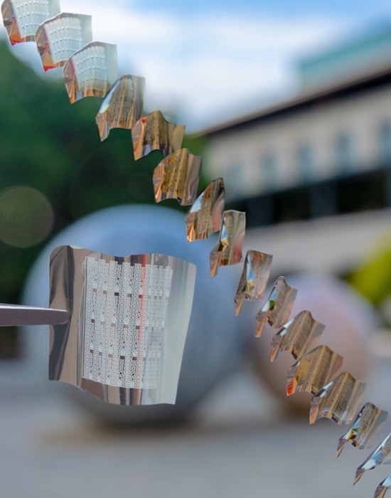 A flexible phase-change memory substrate held by tweezers (left) with a diagonal sequence showing substrates in the process of being bent.  CREDIT Crystal Nattoo