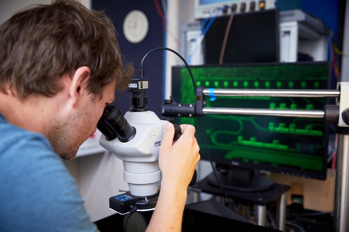 A Toshiba scientist examines a QKD chip under the microscope at the company’s Cambridge Research Laboratory