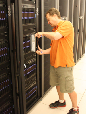 Chad Dougherty, research programmer in the Parallel Data Lab, inserts a blade computer salvaged from the Los Alamos National Laboratory into a rack of the new Narwhal computing cluster.